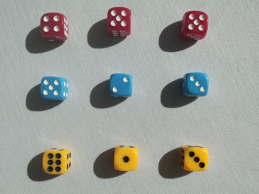 A 3x3 grid of dice. The top three dice are red, the middle three dice are blue, and the bottom three dice are yellow. The numbers on them were chosen randomly.